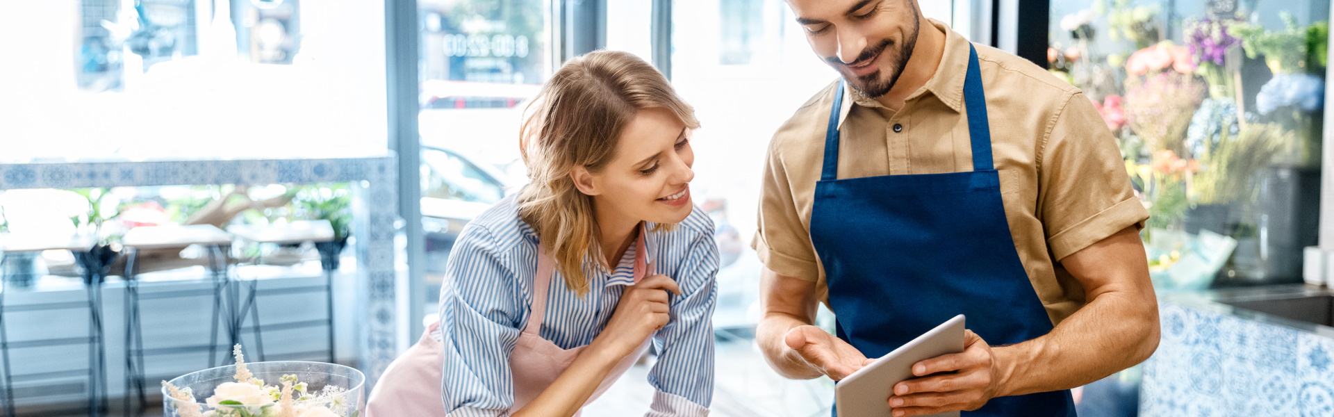 Verkäuferin und Verkäufer im Blumenladen, die auf ein Tablet schauen