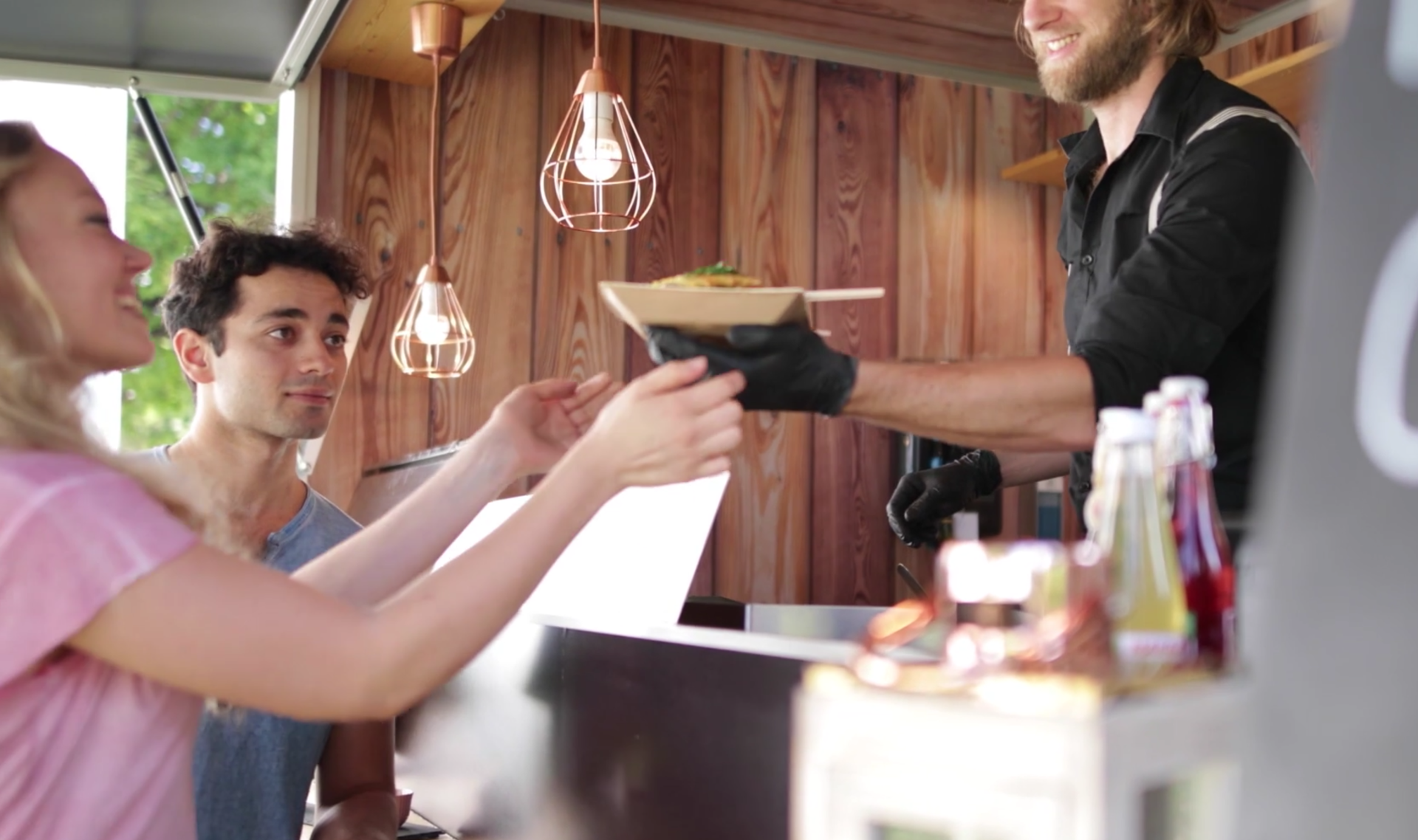Eine Frau nimmt an einem Foodtruck ihre Bestellung entgegen