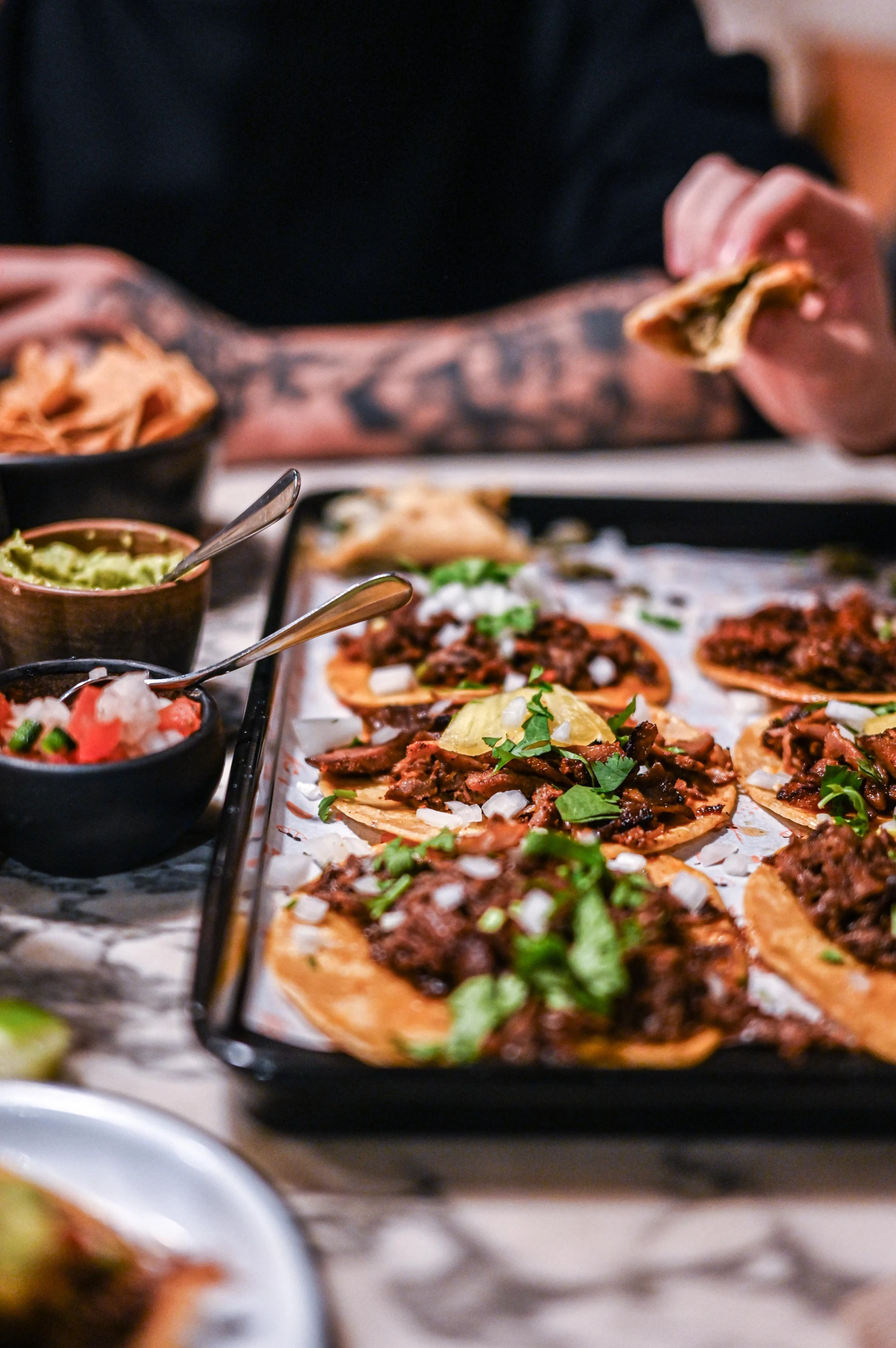 Tacos e varie salse e ingredienti disposti su un tavolo.